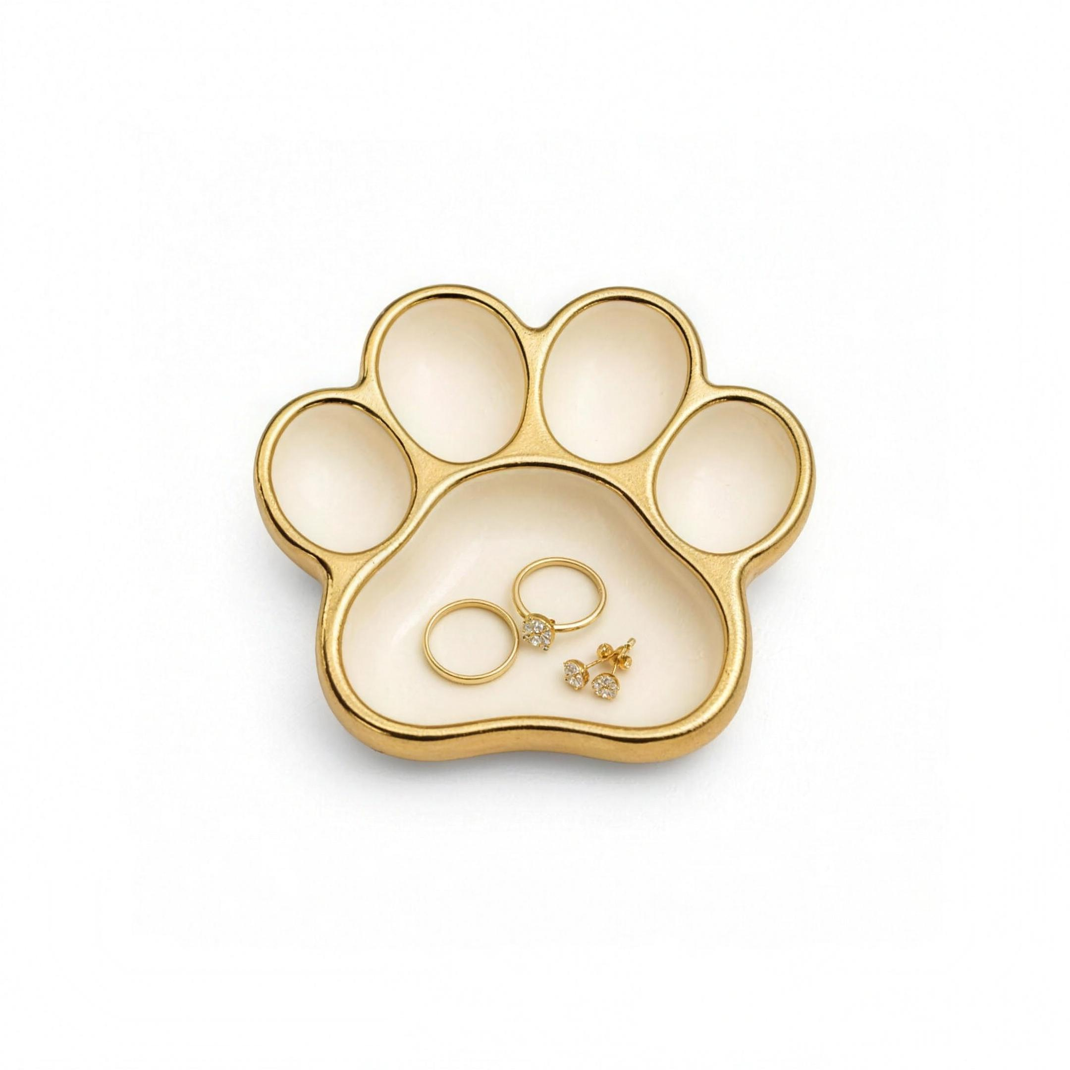 Keepsake Dog Paw Ring Dish in ivory ceramic with a gold rim holding gold rings