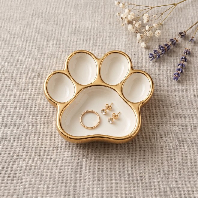Overhead of the Keepsake dog paw ring dish holding a gold ring and stud earrings