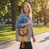 Leo Lion Dog Carrier Tote — a small dog riding in the lion carrier as its owner walks through a park