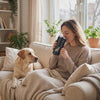 Woman sipping from the Bond dog mom tumbler on the couch with her Labrador beside her