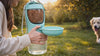 Dog drinking from the Sip portable dog water bottle in a park