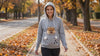 Woman wearing the Nook dog carrier hoodie with her Pomeranian on an autumn walk